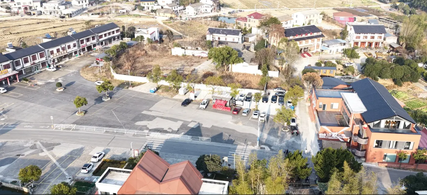 韶山会客厅门前大型停车场航拍实景：景区内划定车位、进出通道与周边街巷，自驾车辆可直接停放